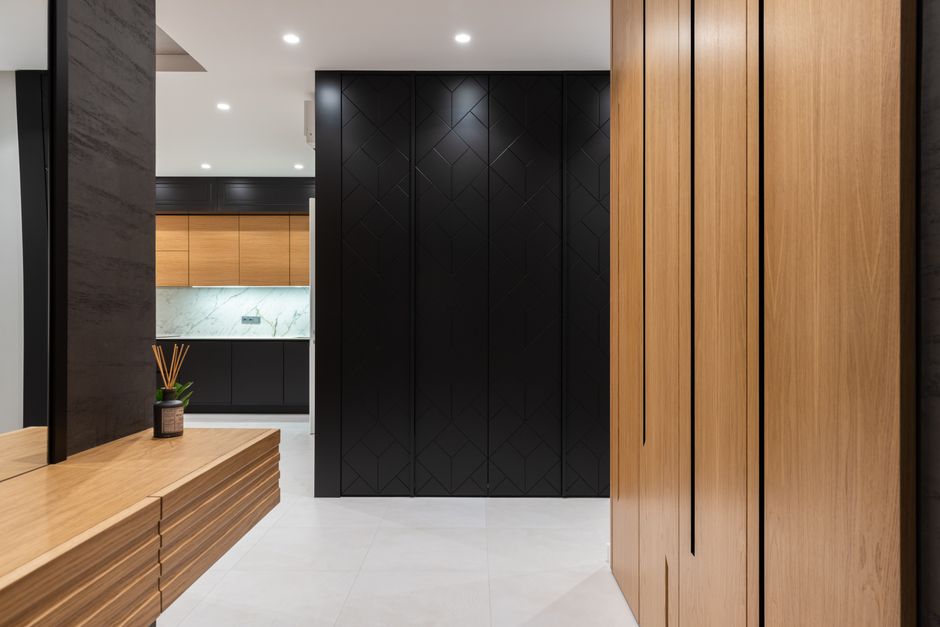 Modern bright apartment interior with big closet and cabinet with mirror placed in hall near entrance to kitchen